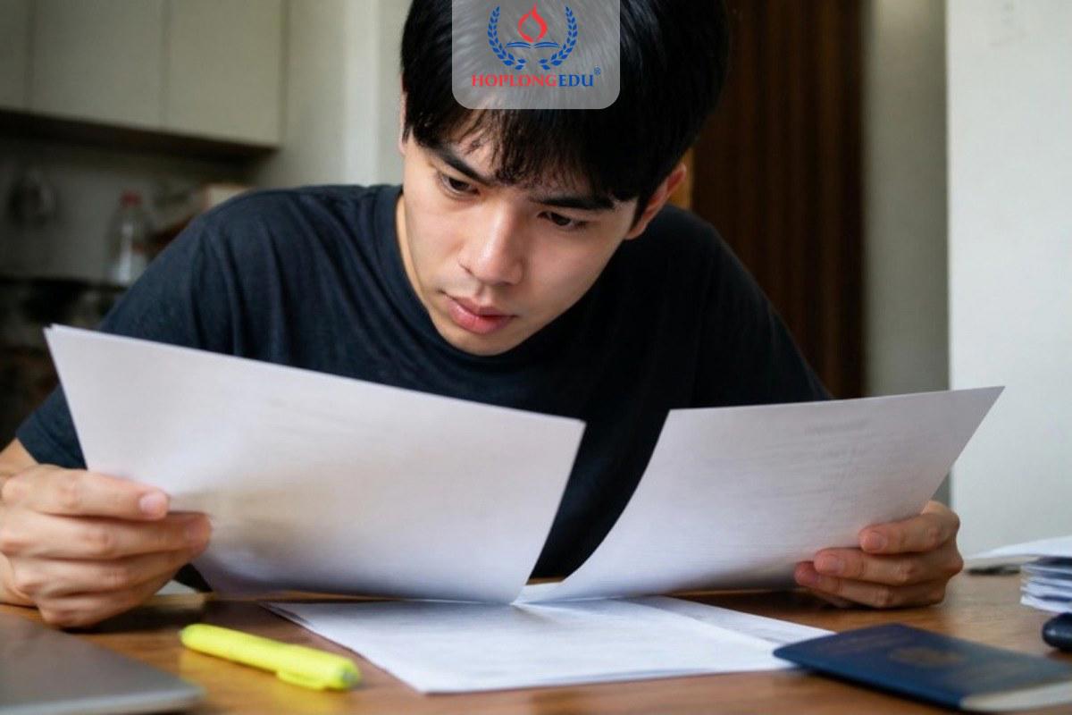 Nam sinh đối chiếu thông tin trên hai tờ giấy trong bộ hồ sơ du học Hàn Quốc