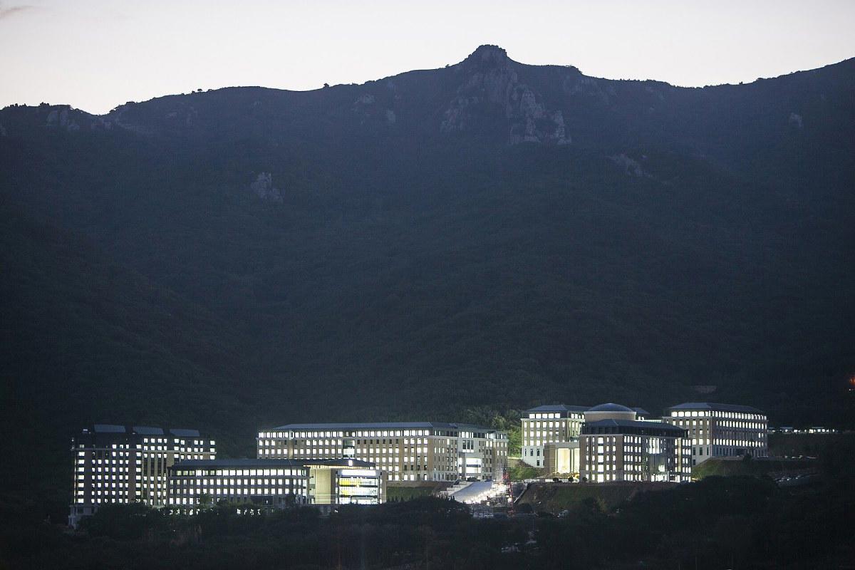 Các tòa nhà Đại học Ngoại ngữ Busan sáng đèn dưới chân núi lúc chiều tối