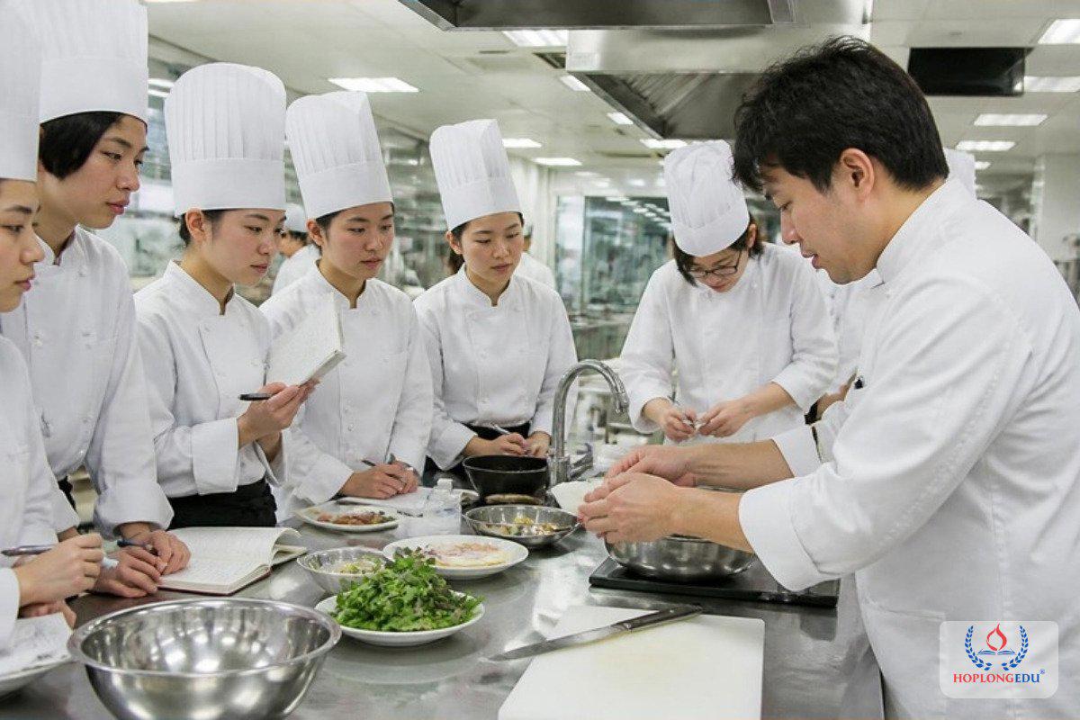 Sinh vi&ecirc;n ng&agrave;nh nấu ăn mặc đồng phục đầu bếp thực h&agrave;nh trong bếp của trường