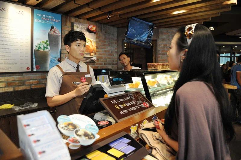 Nhân viên quán cà phê đứng sau quầy bánh phục vụ khách