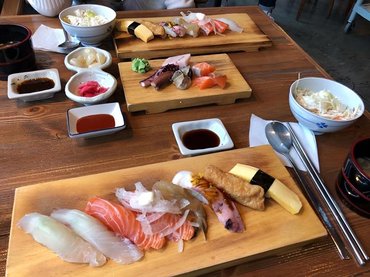 Bàn ăn với đĩa cá sống thái lát, sushi và các món ăn kèm kiểu Hàn