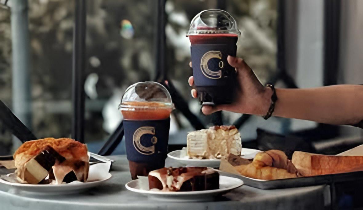 Hai cốc cà phê đá đặt trên bàn cùng vài đĩa bánh ngọt