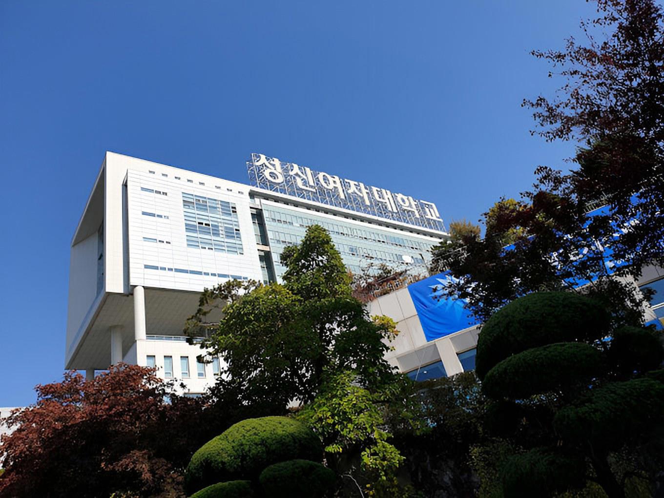 Toà nhà chính Đại học nữ Sungshin với biển tên trường tiếng Hàn trên nóc, phía trước là hàng cây cắt tỉa