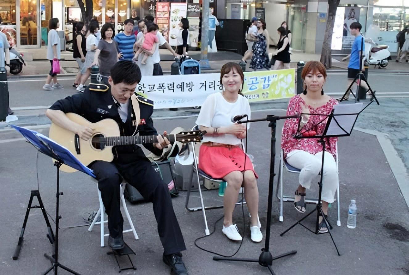 Nhóm nhạc đường phố biểu diễn guitar và hát trên phố đi bộ khu Hongdae, người qua đường dừng lại xem